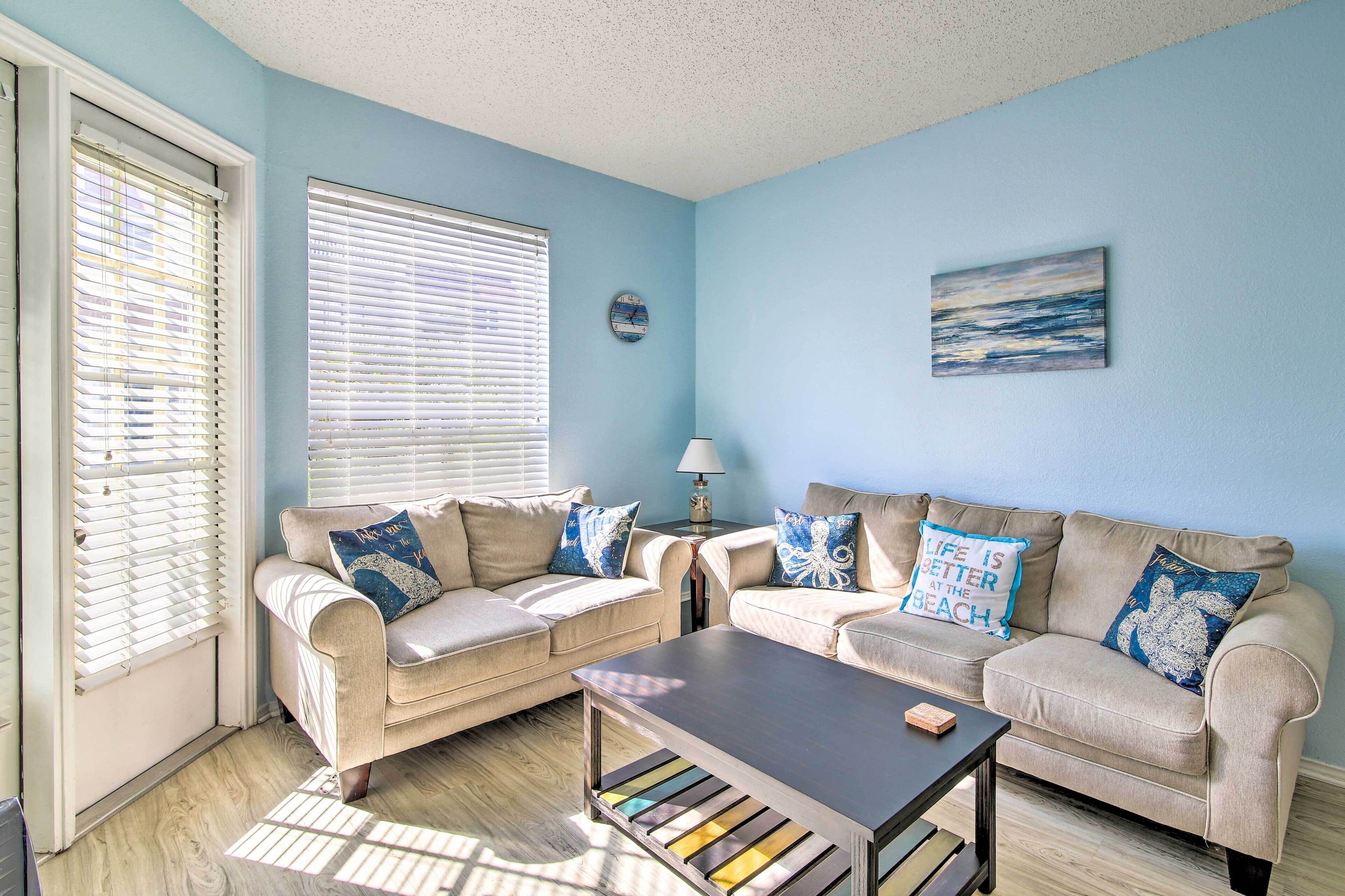 A living room with two beige sofas, a coffee table, and a lamp.