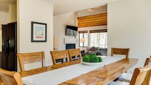 Un coin repas avec une table en bois, des chaises, un set de table blanc et une plante décorative en guise de centre de table.