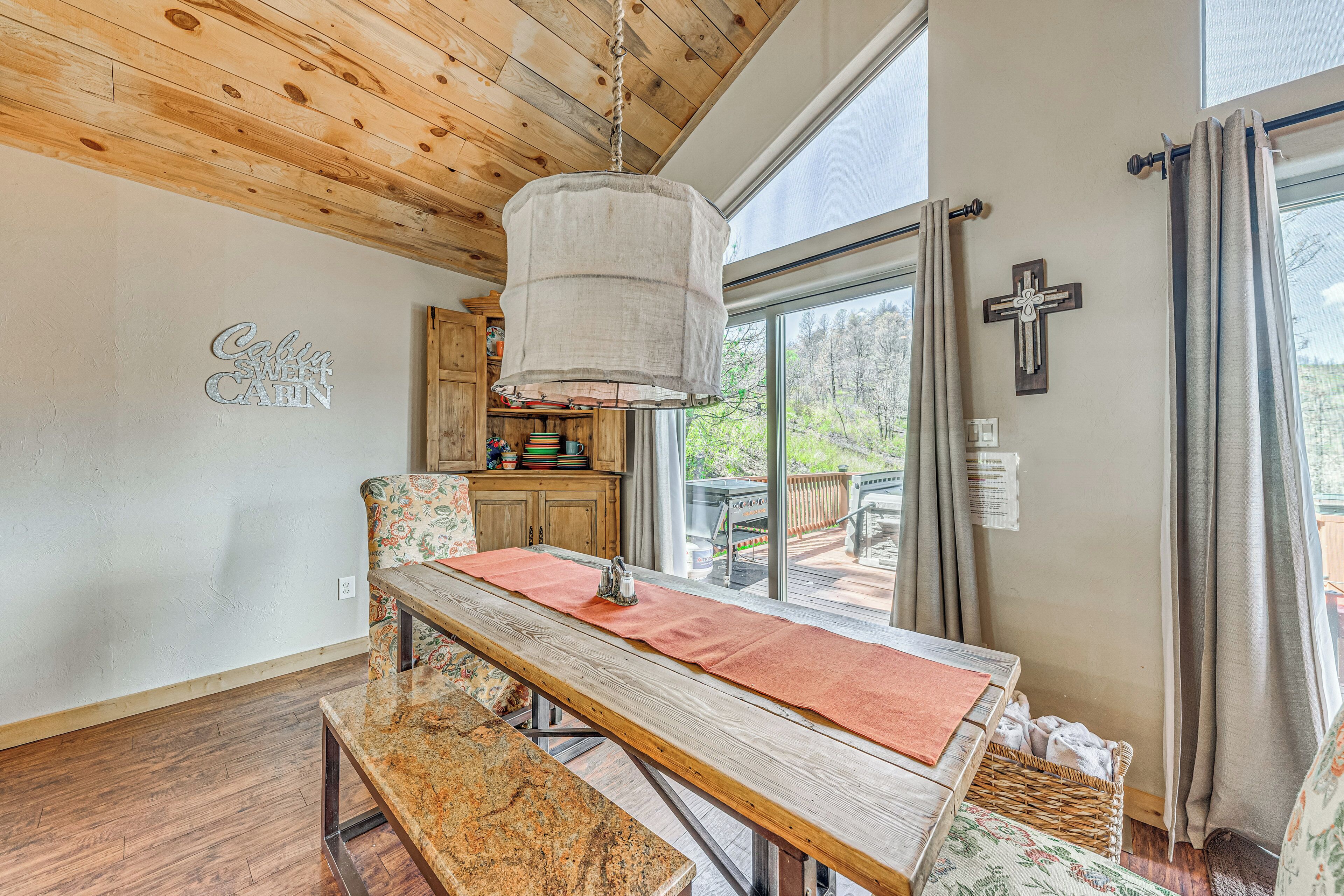 A cozy cabin interior with a wooden dining table, bench, and a hanging light fixture.