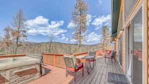 A wooden deck with a hot tub, outdoor seating, and a view of trees and hills. - Ruidoso Cabin w/ Hot Tub, 2 Mi to Grindstone Lake! (Ruidoso)
