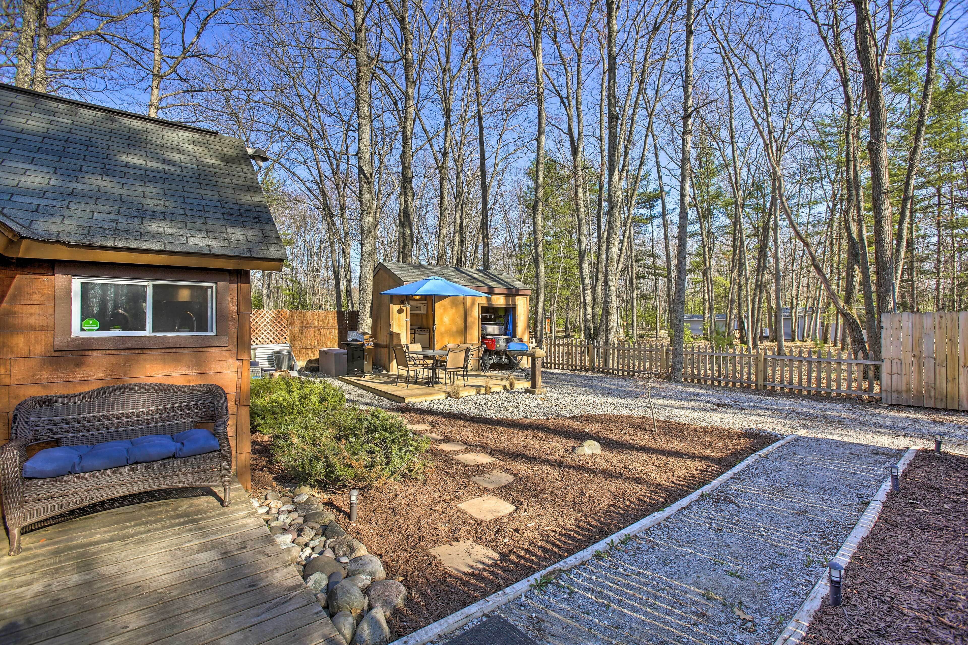 Une cabane en bois dotée d’une terrasse, d’un espace salon extérieur et d’un chemin en gravier.