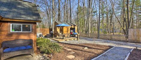 Une cabane en bois dotée d’une terrasse, d’un espace salon extérieur et d’un chemin en gravier.