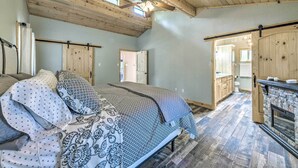 Un dormitorio con cama, techo de madera y vista al baño.