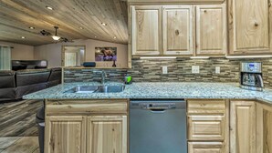 Una cocina con armarios de madera, encimeras de granito y lavavajillas.