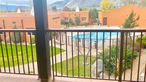 A view of a residential area with a swimming pool, surrounded by greenery and buildings. - 3 Bedroom Townhome in Osoyoos with views! VII (Osoyoos)