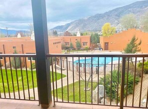 A view of a residential area with a swimming pool, surrounded by greenery and buildings. - 3 Bedroom Townhome in Osoyoos with views! VII (Osoyoos)
