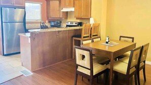 A compact kitchen with wooden cabinets, a stainless steel refrigerator, a microwave, and a stove. There is a dining table with four chairs. - 3 Bedroom Townhome in Osoyoos with views! VII (Osoyoos)