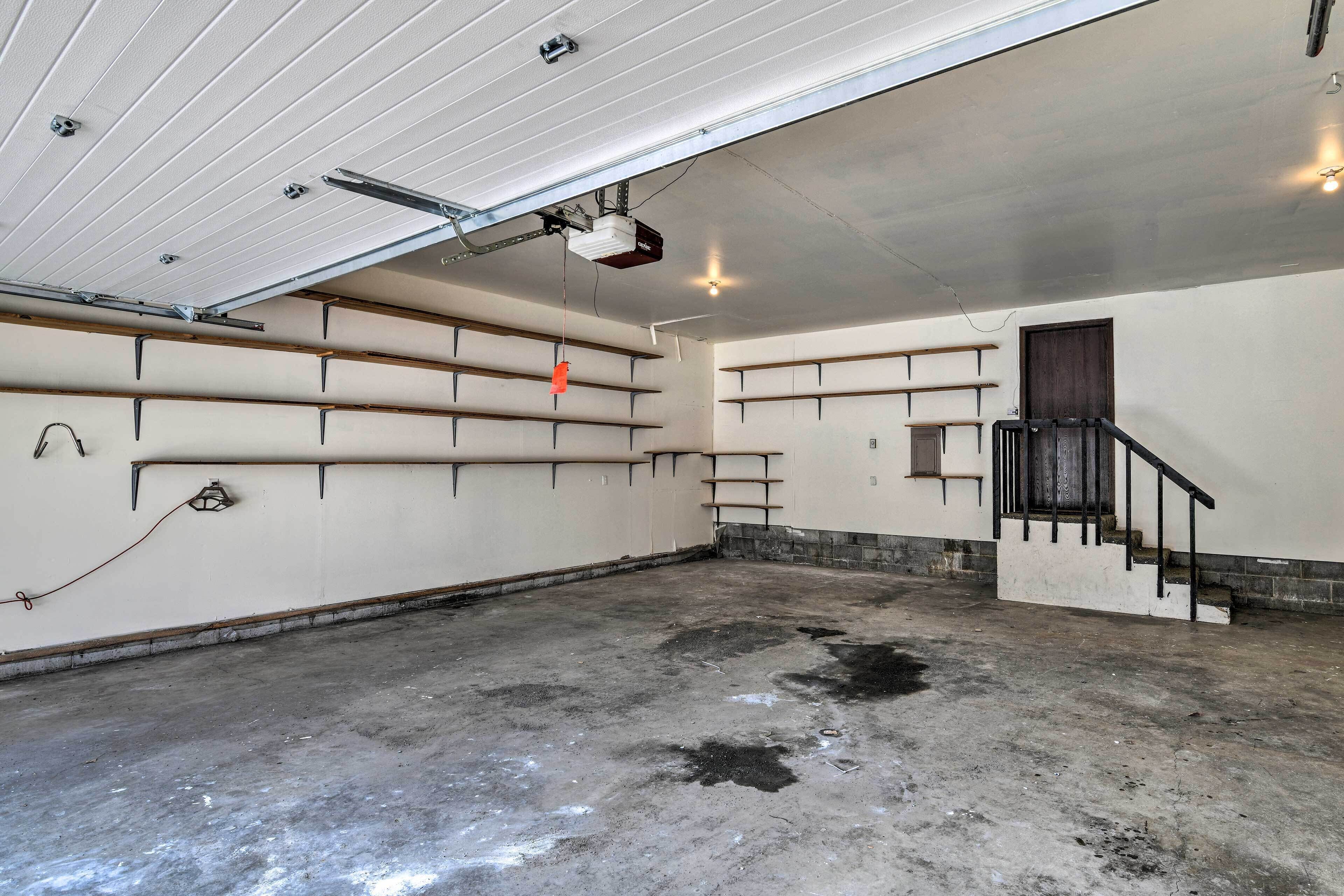 A spacious garage with concrete floors, metal shelving units, and a staircase leading to a door.