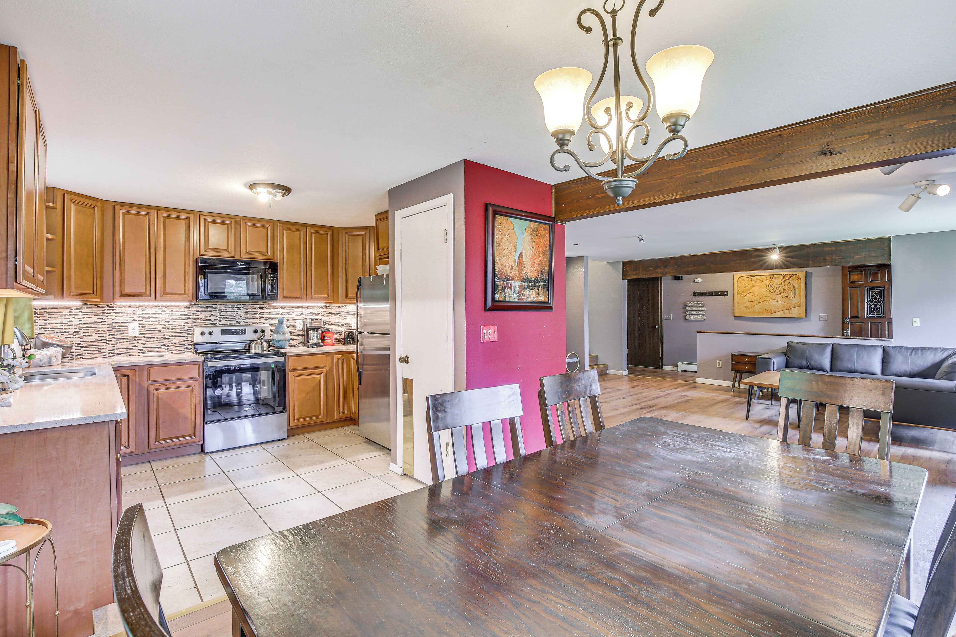 A spacious kitchen with wooden cabinets, a dining area with a large table and chairs, and a living room with a sofa and a coffee table.
