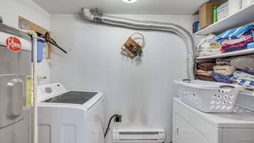 Un lavadero con lavadora, secadora y un calentador de pared.