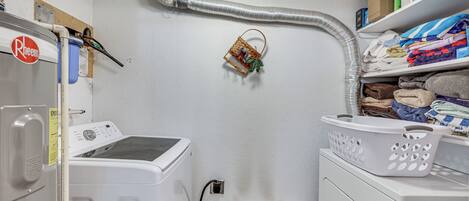 A laundry room with a washing machine, dryer, and a wall-mounted heater.
