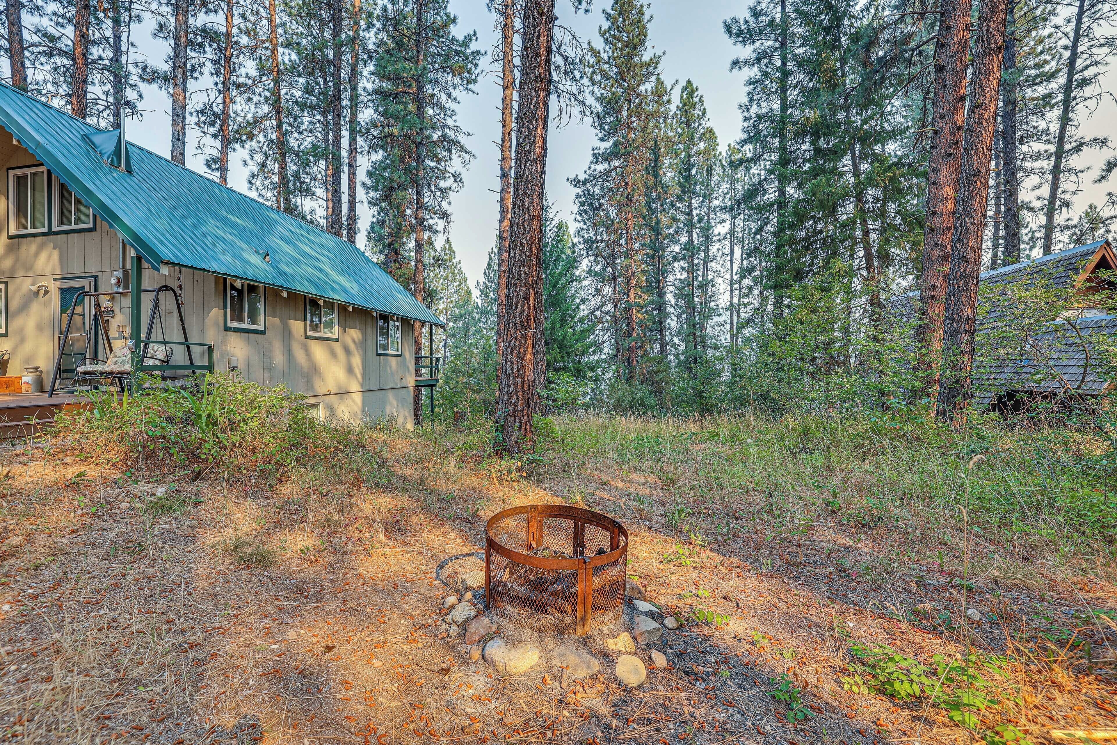 A rustic cabin with a metal roof, surrounded by tall pine trees.