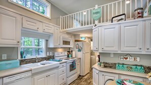 A kitchen with white cabinets, a microwave, an oven, and a sink. There is a window above the sink, and a sign above the cabinets that says "This is my happy place." - Cozy Broken Bow Getaway w/ Fire Pit, 5 Mi to Lake! (Broken Bow)