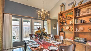 A dining room with a wooden table set for four, a chandelier, and a bookshelf with various items. - Lubbock Townhome w/ Grill Near TTU & Downtown! (Lubbock)