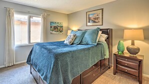 A bedroom with a bed, a nightstand, a lamp, and a window with curtains. - Lubbock Townhome w/ Grill Near TTU & Downtown! (Lubbock)