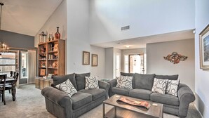 A spacious living room with two grey sofas, a coffee table, and a bookshelf filled with decorative items. - Lubbock Townhome w/ Grill Near TTU & Downtown! (Lubbock)