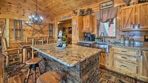 A rustic wooden interior with a stone island, wooden furniture, and a chandelier.