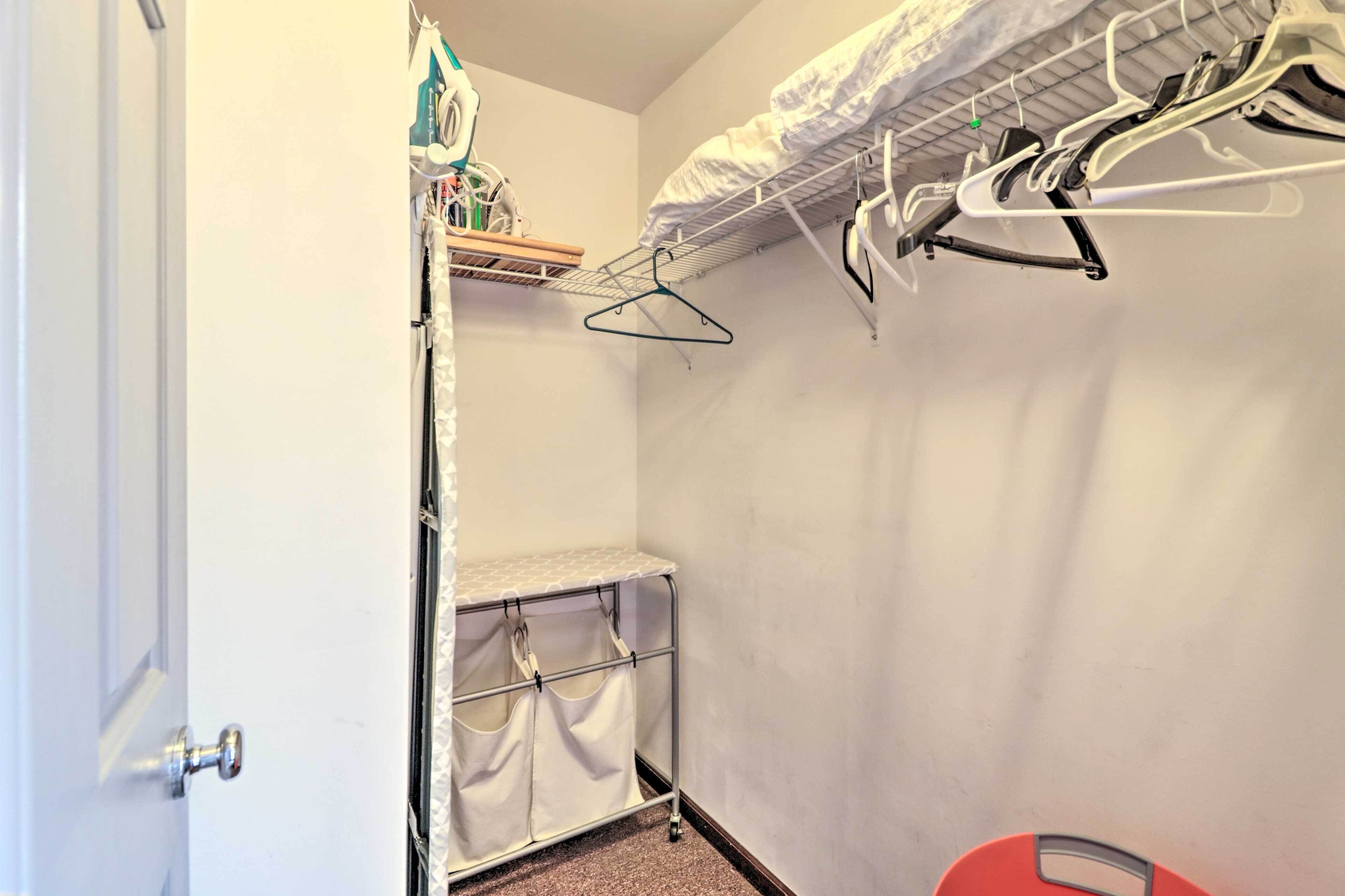 A compact room with a bed, a small shelf, and a drying rack.