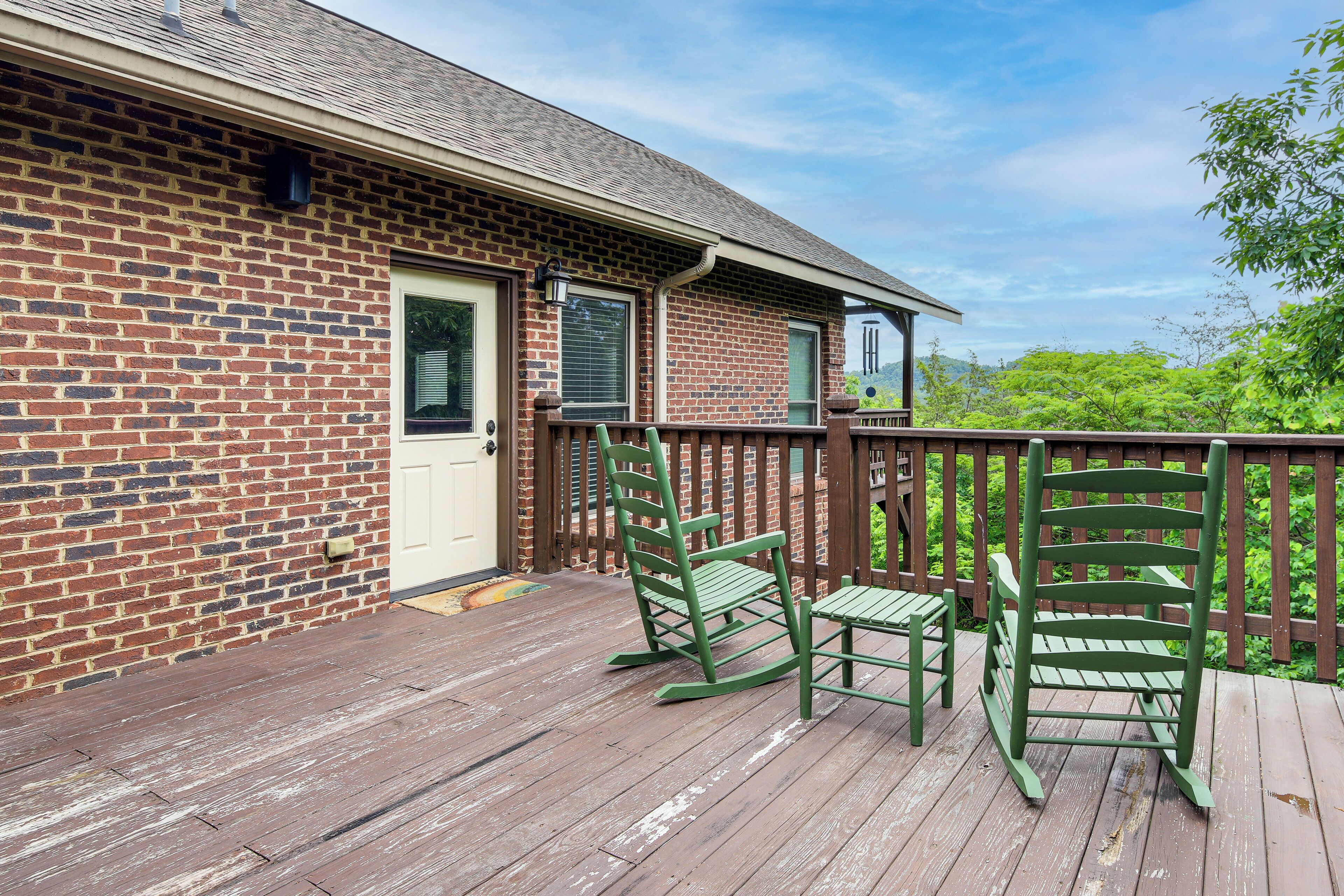 A brick building with a wooden deck, two rocking chairs, and a door.