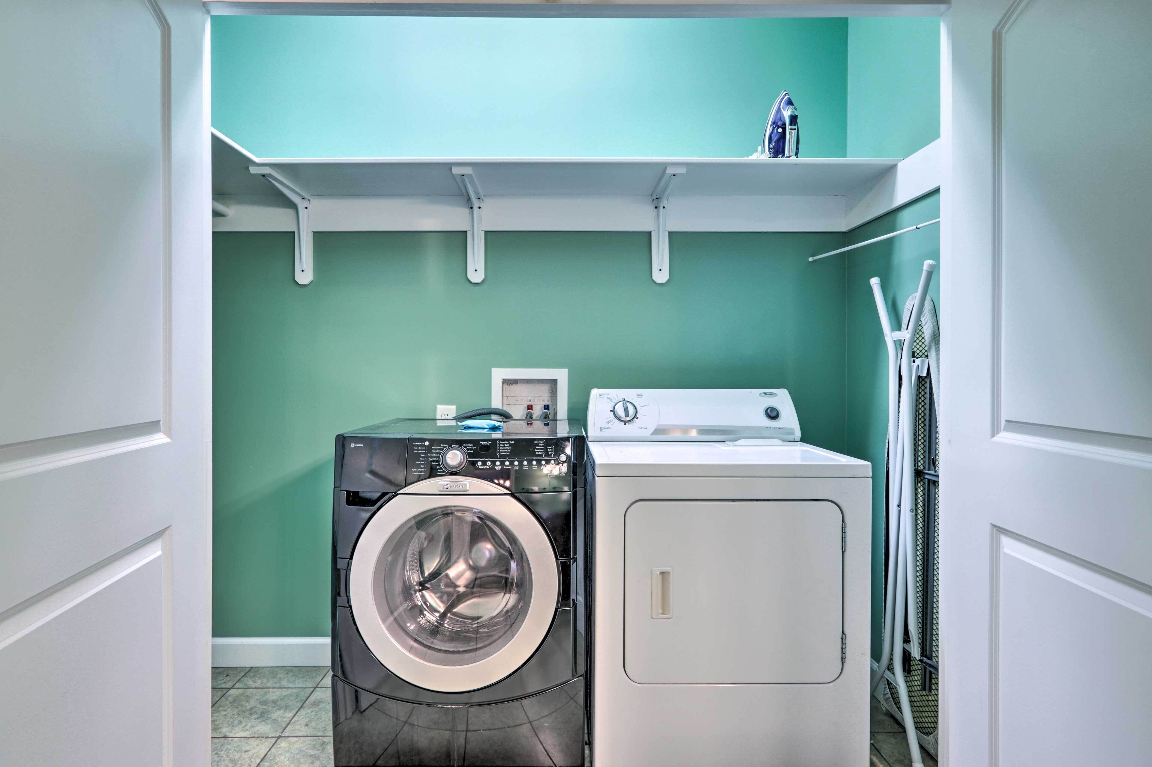 A laundry room with two washing machines, a shelf above, and a wall-mounted drying rack.