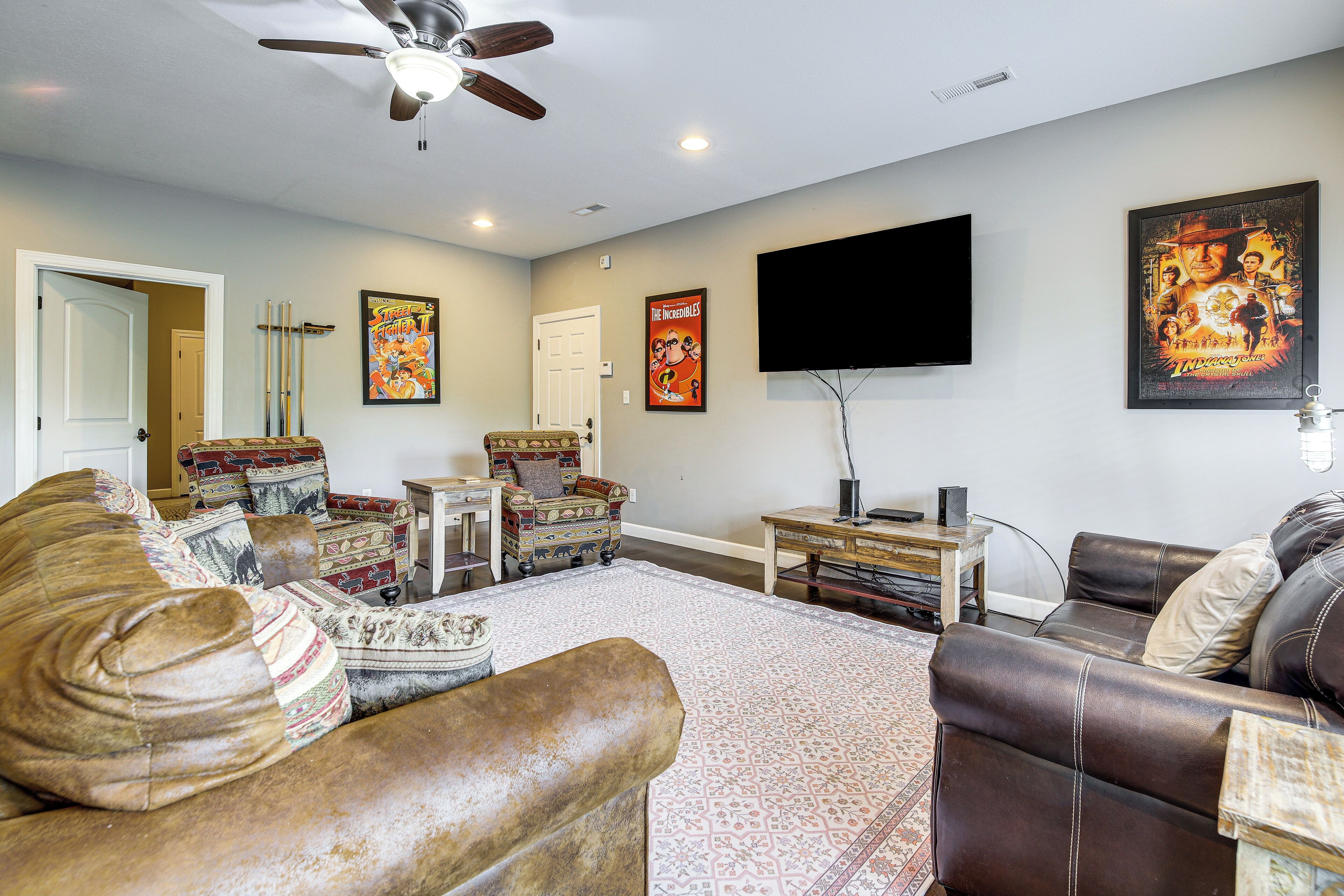 A living room with a ceiling fan, a flat-screen TV, patterned sofas, and a rug.