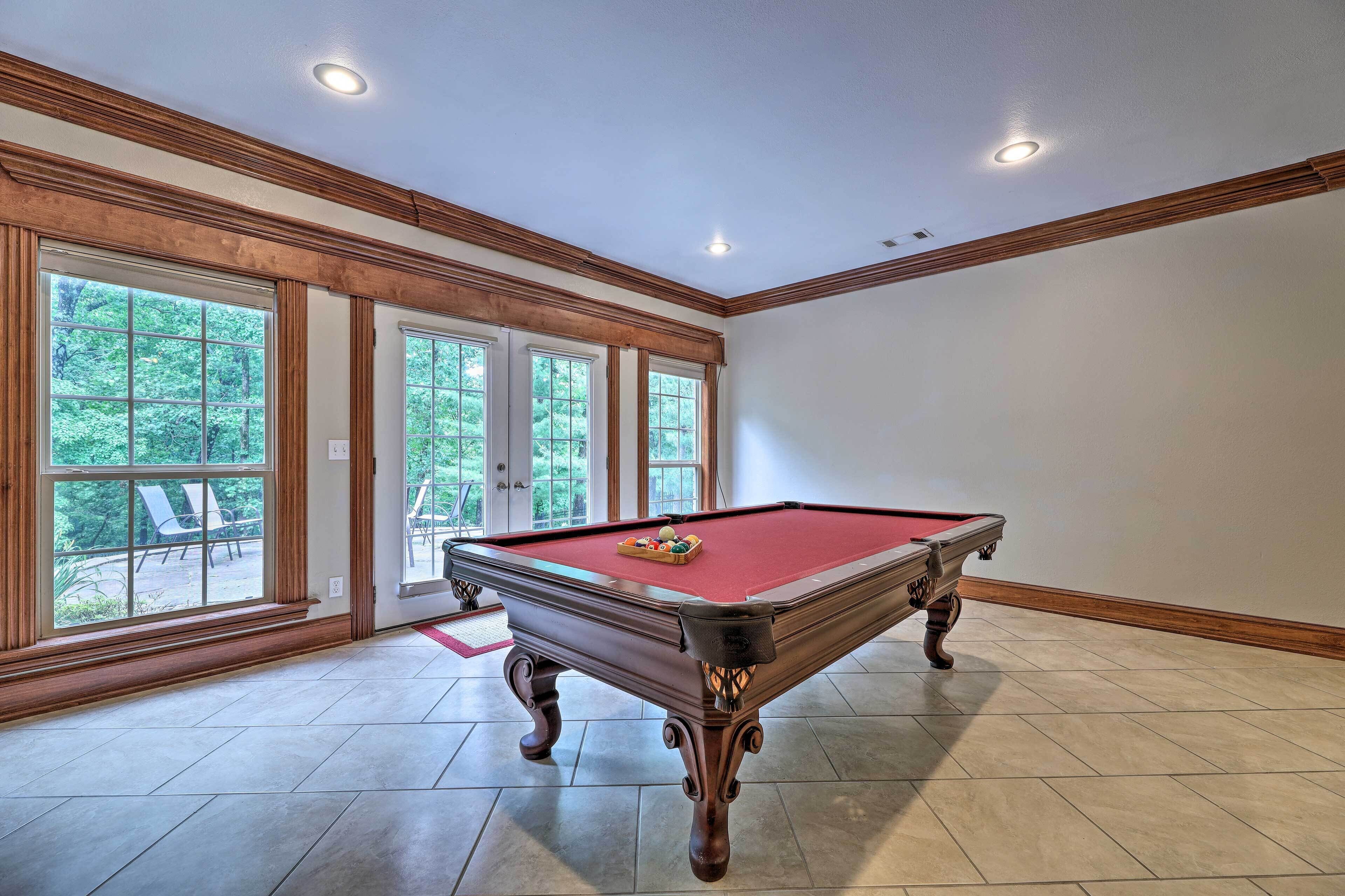 Une table de billard dans une pièce dotée de grandes fenêtres donnant sur un paysage verdoyant.