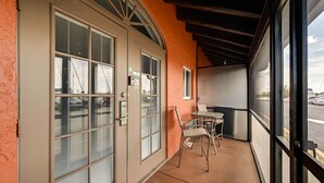 A covered outdoor area with a table and chairs, a sliding glass door, and a view of the street. - Studio w/ Marina Views: 15 Mi To Everglades! (Naples)