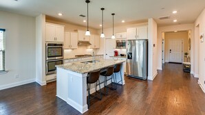 A modern kitchen with white cabinets, stainless steel appliances, and a central island with bar stools. - Nolensville Home w/ Free Wifi: 20 Mi to Nashville! (Nolensville)