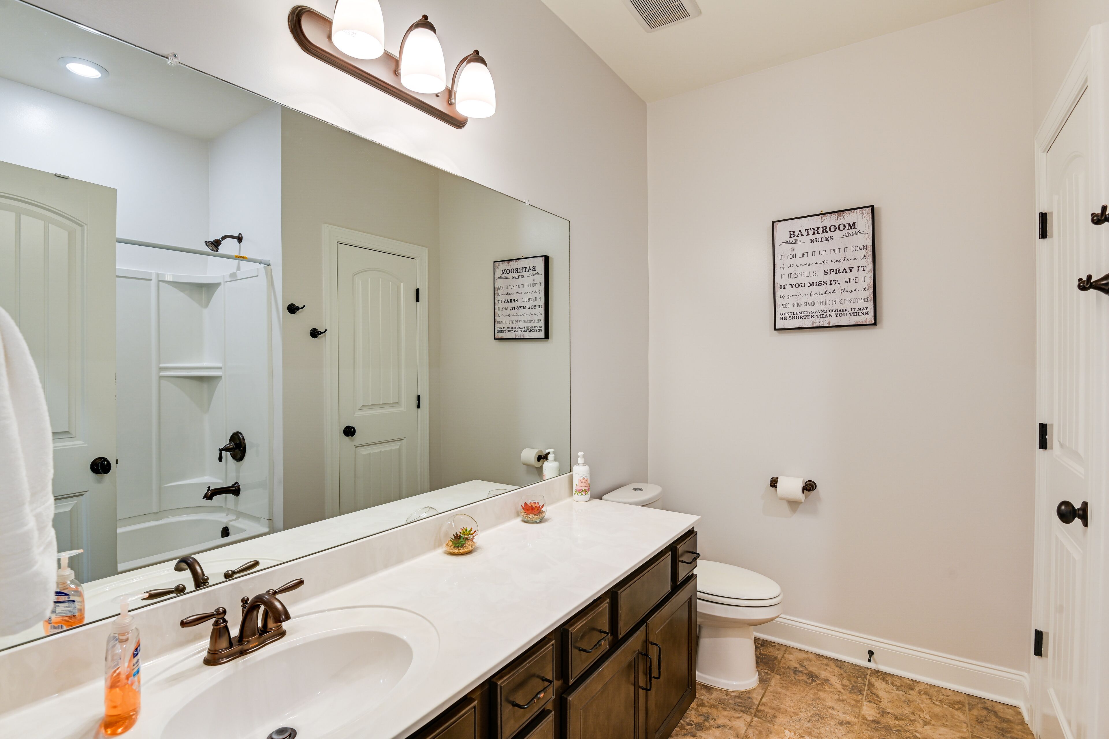 A bathroom with a white sink, a mirror, a toilet, and a shower area.