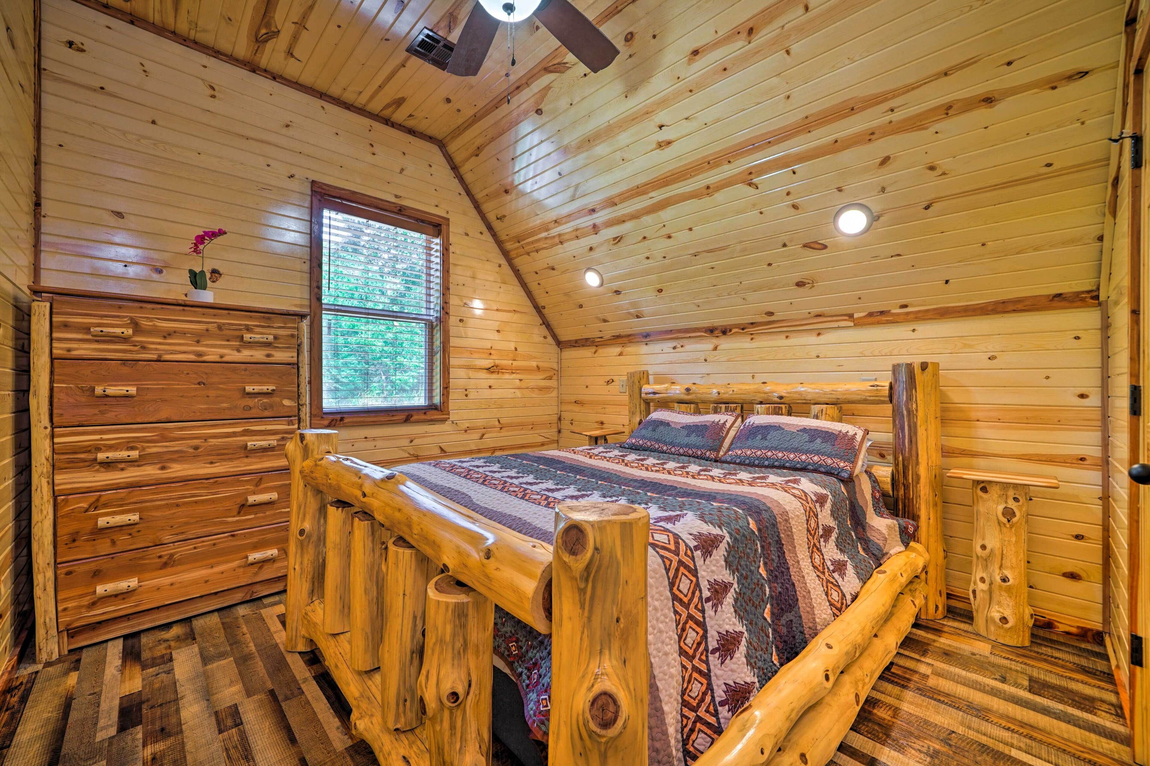 A wooden cabin bedroom with a bed, dresser, and window.