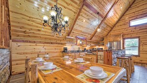 A wooden interior with a long dining table set for four, a chandelier, and a stone wall. - Talihina Retreat w/ Kiamichi River Access! (Talihina)