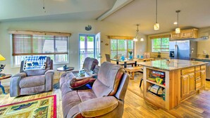 A spacious living area with leather recliners, a dining table, and a kitchen with wooden cabinets. - Awesome Hoodsport Cabin - Nearby Hiking Areas (Hoodsport)