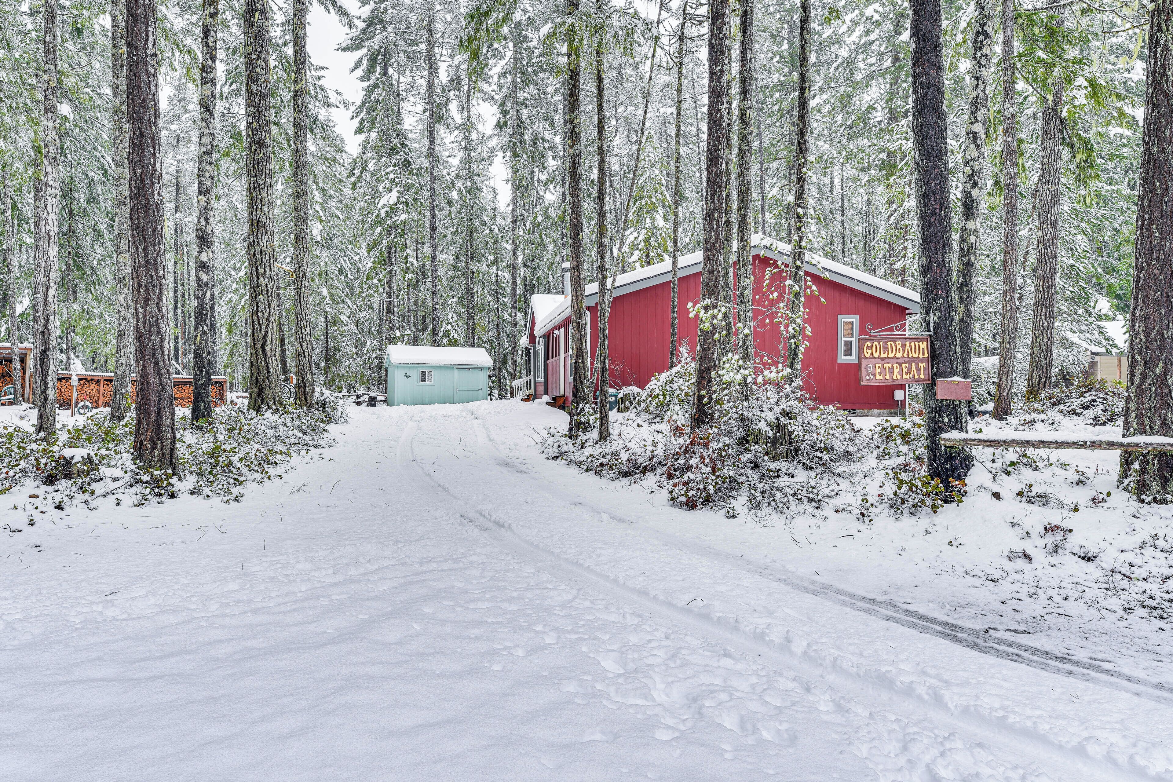Lumipeitteinen metsä, jonka keskellä on punainen rakennus, jossa on kyltti, jossa lukee: ”Goldbaum Retreat”.