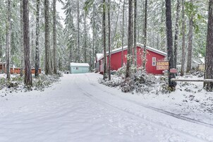 Une forêt enneigée avec un bâtiment rouge portant l’inscription « Goldbaum Retreat ».