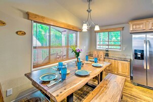 Una cocina con encimeras de madera, un refrigerador de acero inoxidable y una zona de comedor con un banco de madera y cristalería azul.