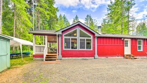 A red cabin with a porch, a covered outdoor seating area, and a gravel driveway. - Awesome Hoodsport Cabin - Nearby Hiking Areas (Hoodsport)