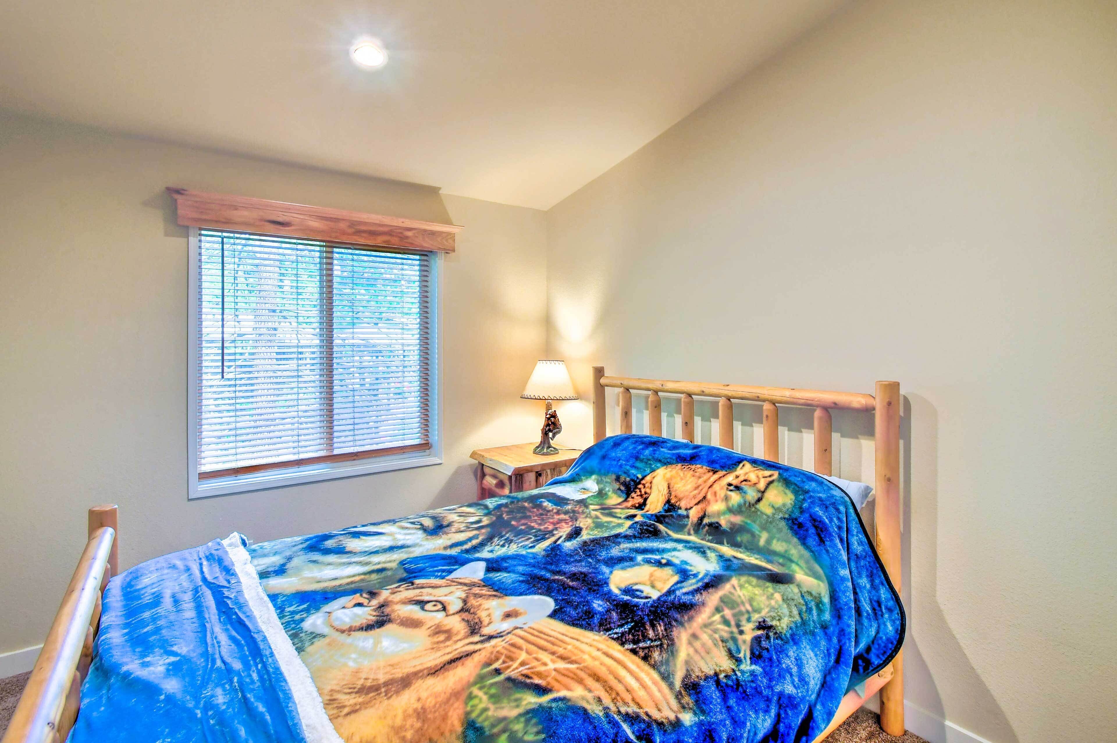 Une chambre à coucher avec un lit en bois, une fenêtre avec des stores, une lampe de chevet et une couvre-lit aux couleurs vives.