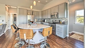 A modern kitchen with a central island, bar stools, stainless steel appliances, and a view to the outdoors. - Peaceful Hill Country Hideaway w/ Pond Views (Wimberley)
