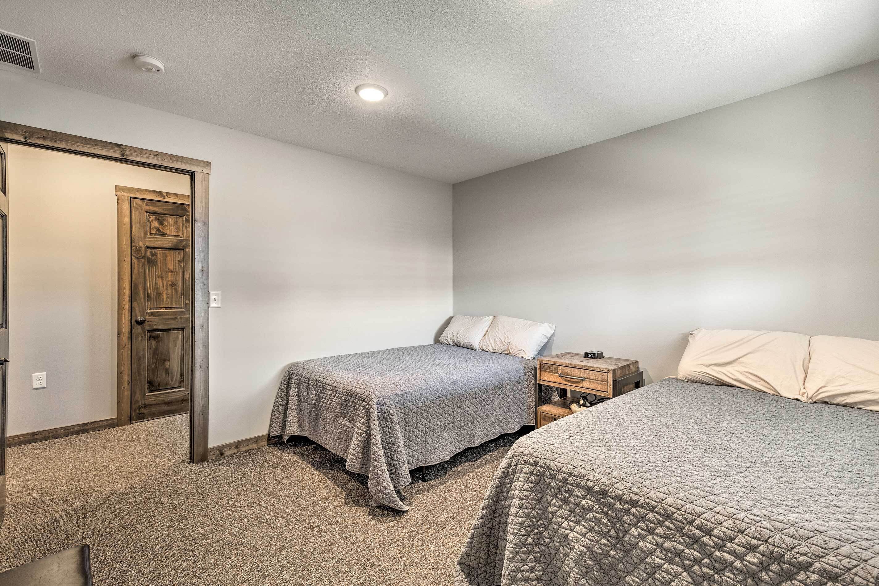 A bedroom with two beds, a wooden door, and a nightstand.