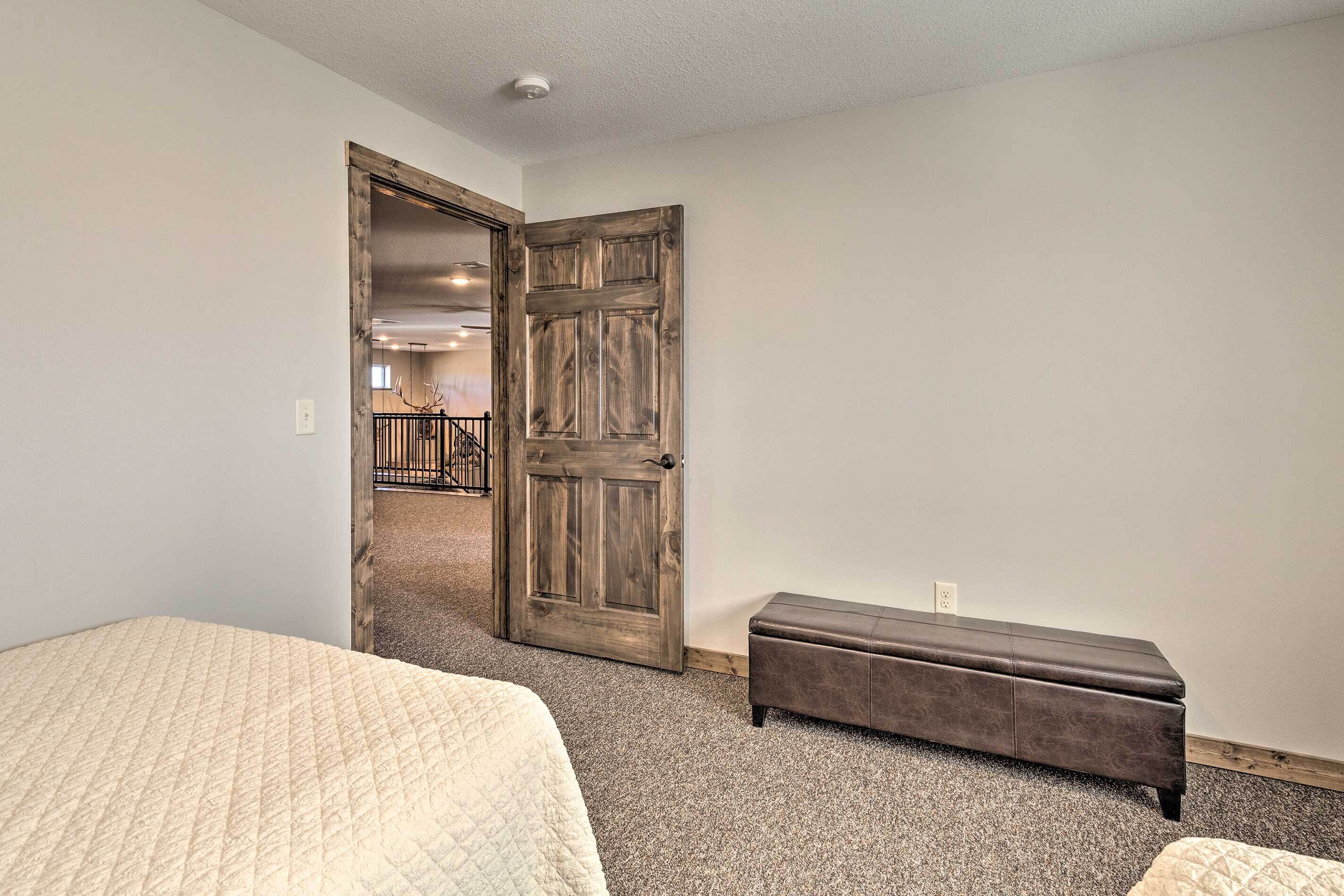A bedroom with a large bed, a bench, and a wooden door leading to a balcony.