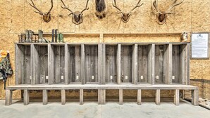 A wooden bench with multiple compartments, mounted on a wall with mounted animal heads. - Kansas Hunting Lodge: Pets & Large Groups Welcome! (Great Bend)