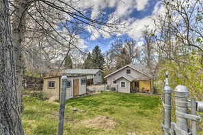 A residential area with two houses, a fenced yard, and a tree. - Pet-friendly Cody Home - Walk to Main Street! (Cody)
