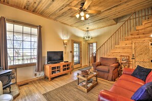 A cozy living room with wooden floors, a television, a fireplace, and a staircase. - Pet-friendly Cody Home - Walk to Main Street! (Cody)