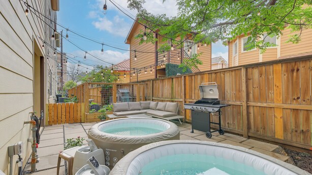 A backyard with two hot tubs, a barbecue grill, and a wooden fence. - Houston Vacation Rental ~ 1 Mi to Downtown! (Houston)