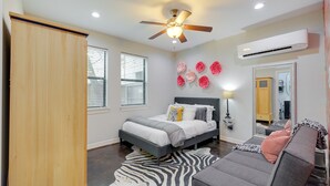 A bedroom with a bed, a ceiling fan, an air conditioner, a zebra rug, and a mirror. - Houston Vacation Rental ~ 1 Mi to Downtown! (Houston)