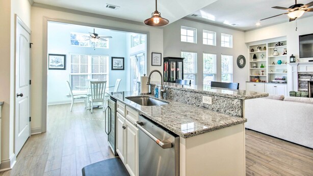 A modern kitchen with granite countertops, stainless steel appliances, and a dining area with white chairs. - North Augusta Getaway w/ Large Deck & Yard (North Augusta)