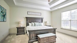 A bedroom with a large bed, two bedside tables, a bench, a ceiling fan, and a window with blinds. - North Augusta Getaway w/ Large Deck & Yard (North Augusta)