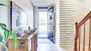 A hallway with a decorative mirror, a wooden console table with a rock display, and a staircase with a wooden railing. - 4 Mi Shuttle Ride to Ocean: Bethany Beach Getaway (Millville)