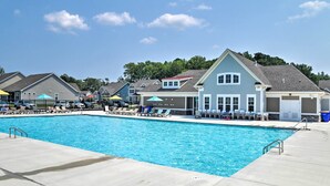 A swimming pool with lounge chairs and umbrellas, surrounded by houses with a clear sky. - 4 Mi Shuttle Ride to Ocean: Bethany Beach Getaway (Millville)