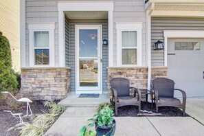 A two-story house with a stone facade, a front door, and two wicker chairs on the porch. - 4 Mi Shuttle Ride to Ocean: Bethany Beach Getaway (Millville)